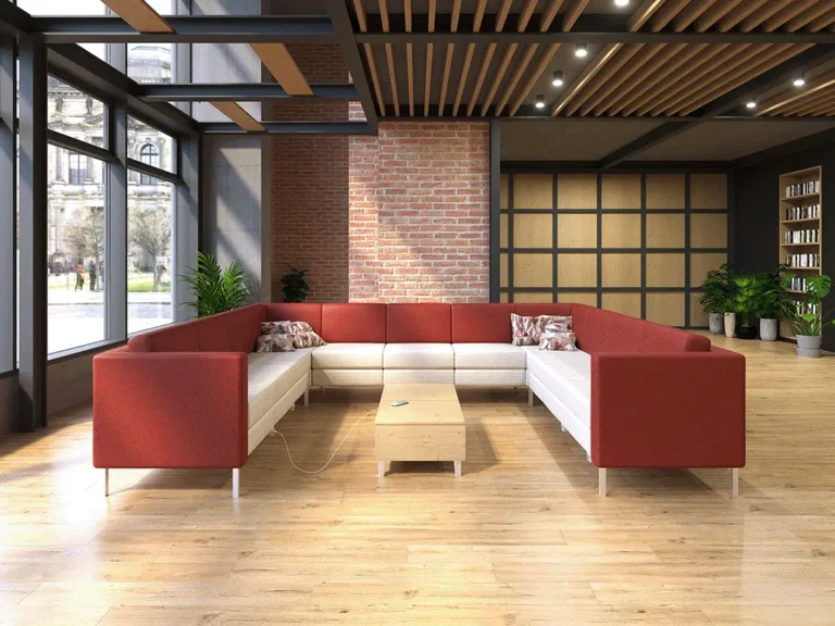A flexible seating solution for collaborative work or casual meetings, featuring a modular sofa with red and white cushions, convenience power, a wooden coffee table, and potted plants in a contemporary office environment.