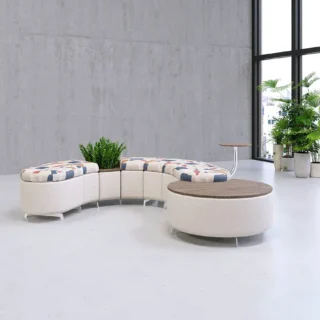 Flexxform Flo modular seating with white and multicolored fabric. Modular seating includes curved piece with planter, big round with table top and a tablet arm.